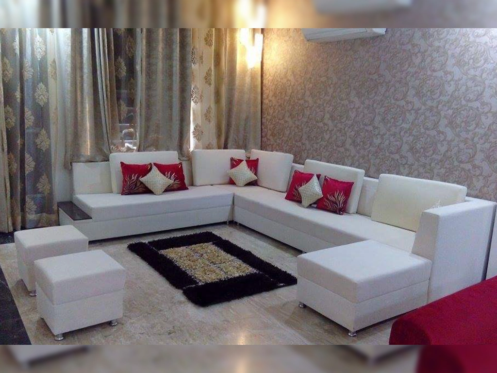 full furnished white color nine seater sofa set with red cushion in hall area.