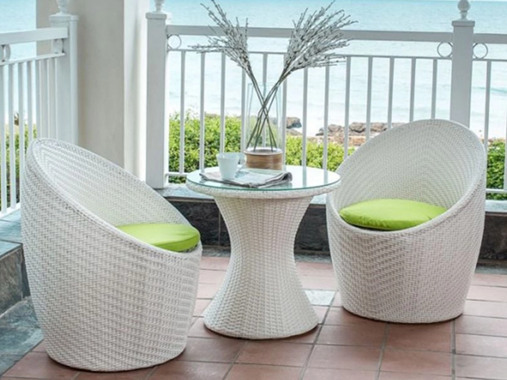 White color wicker egg design chair with green color cushion and white color table with glass on top.