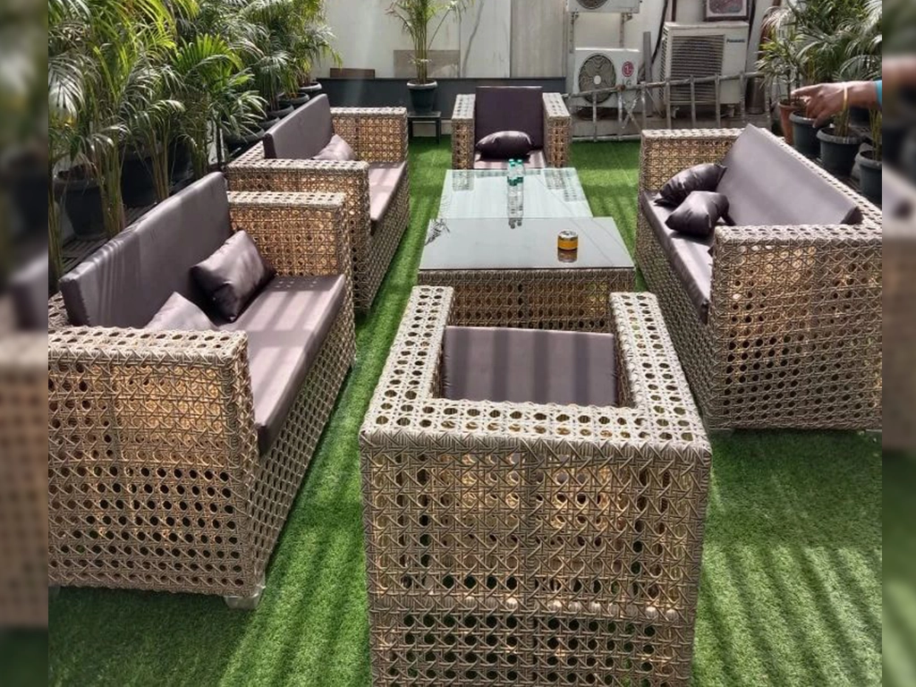 eight seater outdoor beige colour sofa with light rose colour cushion in back and seat, and two centre table with glass top for garden area.